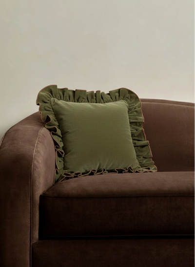 Brown sofa with a 22x22 green pillow against a white wall