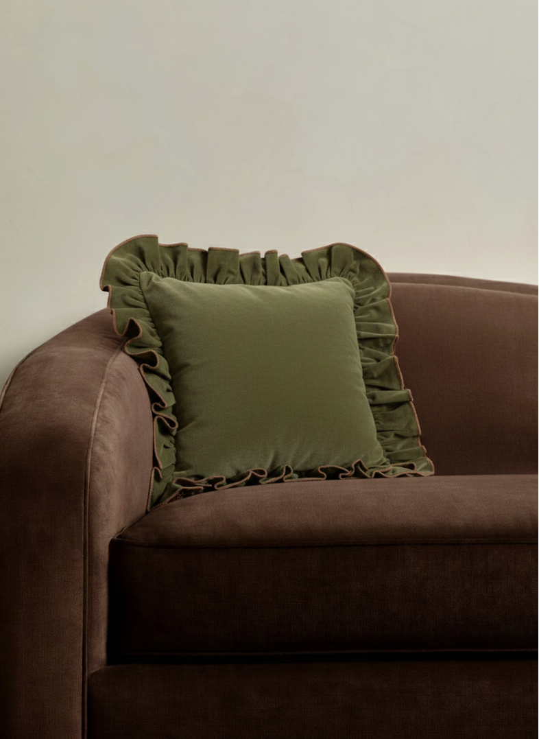Brown sofa with a 22x22 green pillow against a white wall